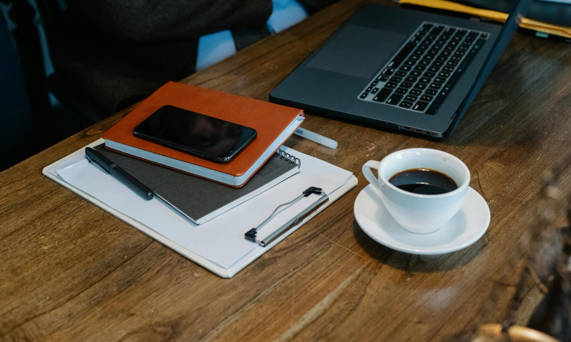Image of Desk with coffee, computer, and note pads.
